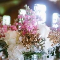 Pink and white floral arrangement with gold accents in a softly lit indoor setting
