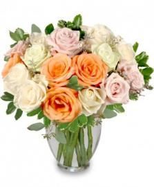 Bouquet of peach, pink, and white roses in a clear glass vase