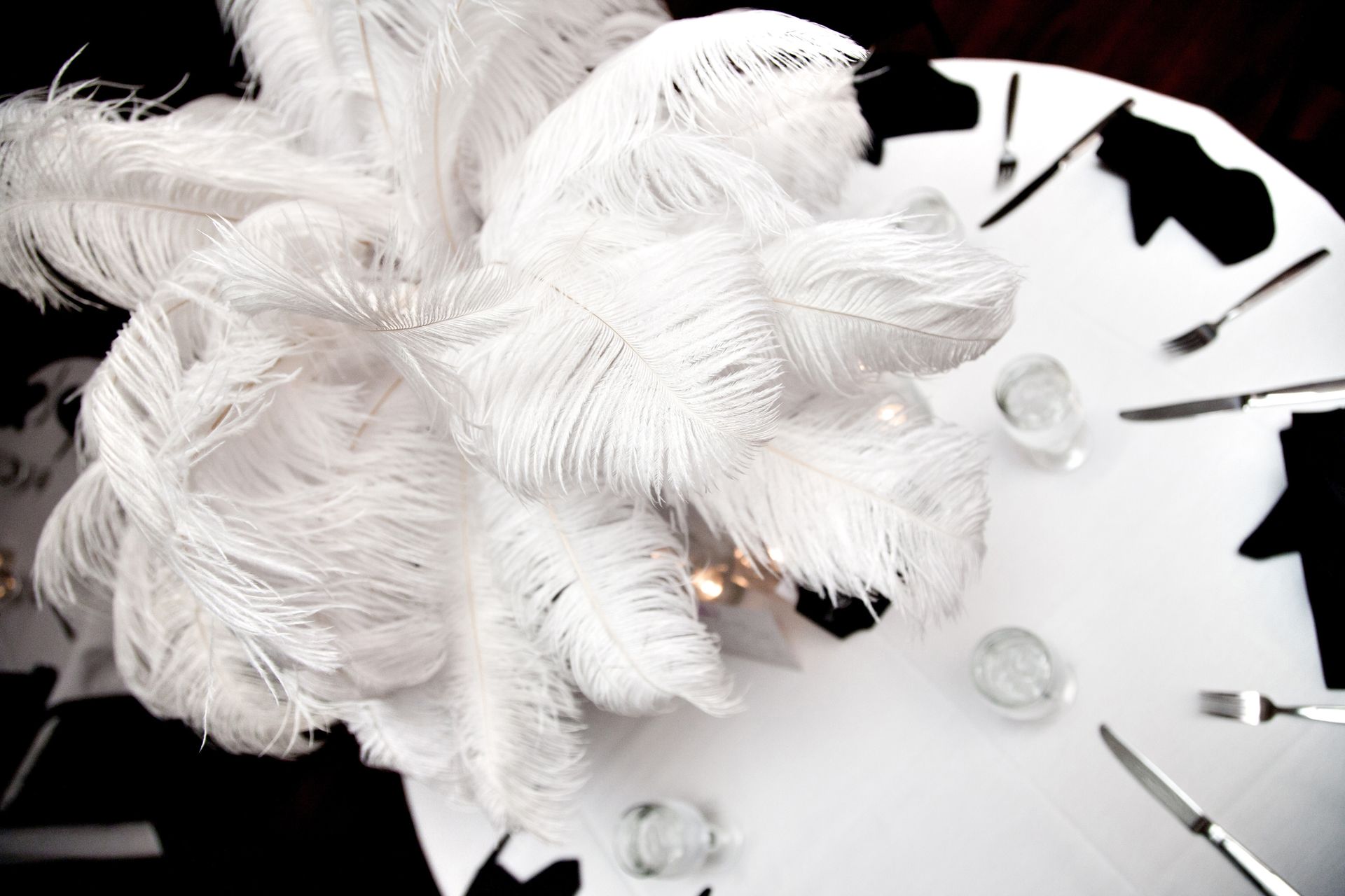 White feather flower arrangement on a black-and-white clock face with scattered glass beads