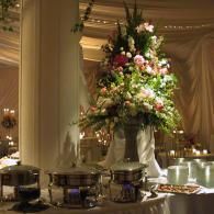 Elegant banquet table with a tall floral centerpiece in a softly lit draped reception hall