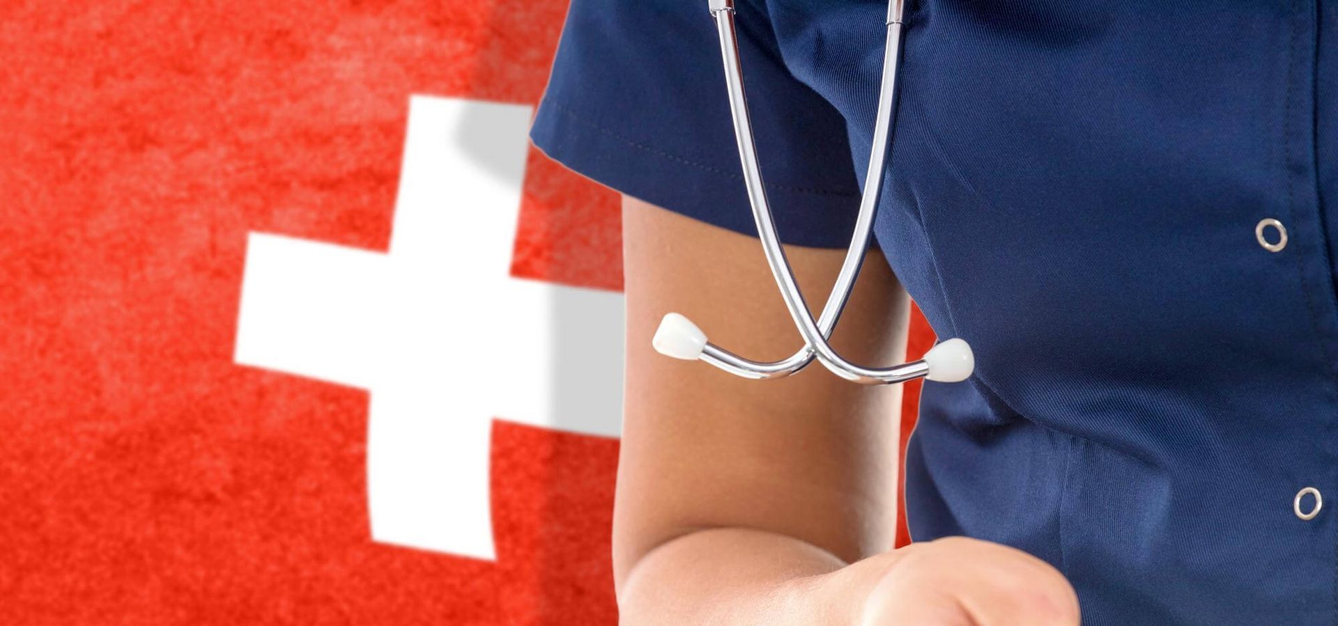 Doctora en batas azules con estetoscopio delante de la bandera roja suiza con cruz blanca