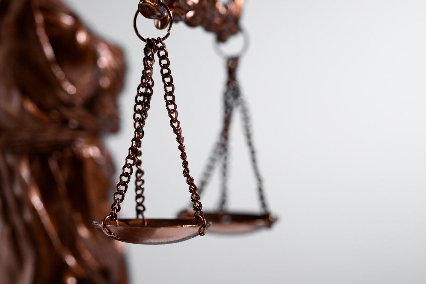 Nahaufnahme einer bronzenen Justitia-Waage vor verschwommenem Hintergrund