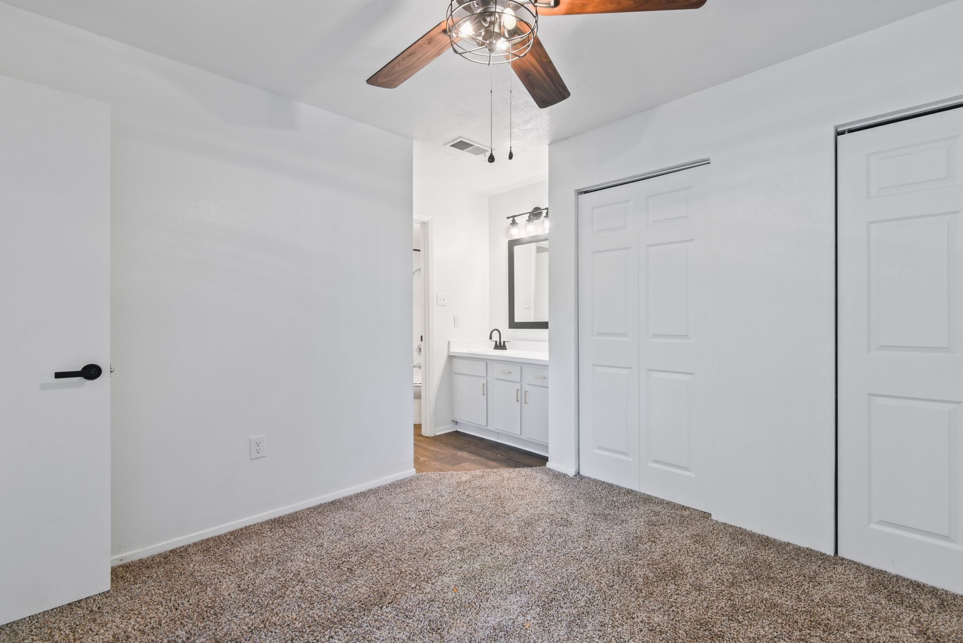 Bedroom with brown carpet, white walls, closet doors, and bathroom entrance.