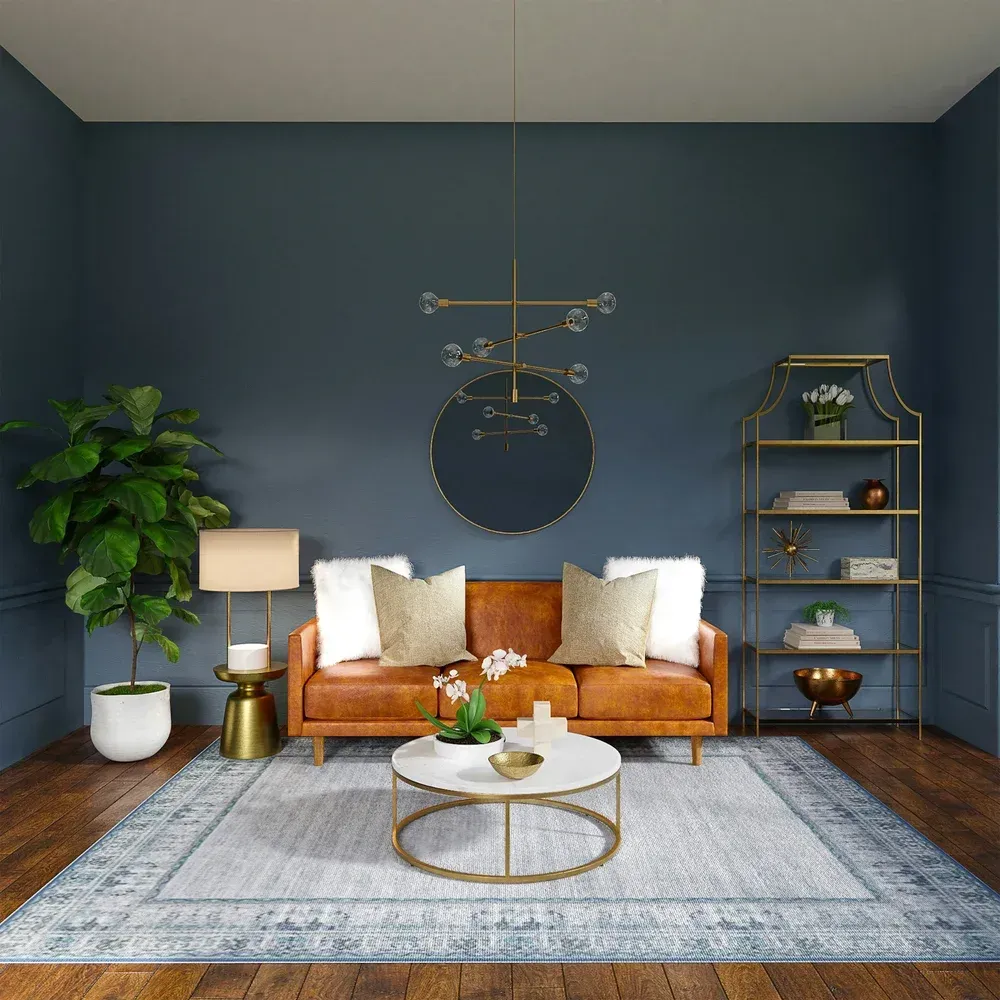 Cozy living room with blue walls, tan sofa, white rug, gold decor, plants, and shelves.