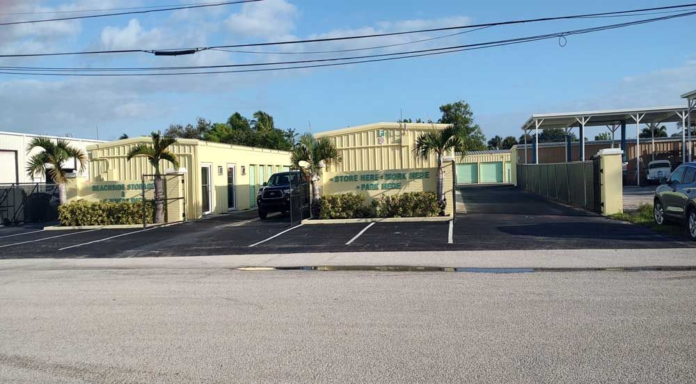 Gated building with palm trees and a parking lot under a clear sky