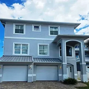 Two-story gray house with white trim, garage, front porch, and blue sky overhead