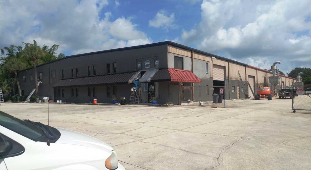 Commercial building with red awning and parking lot under a partly cloudy sky