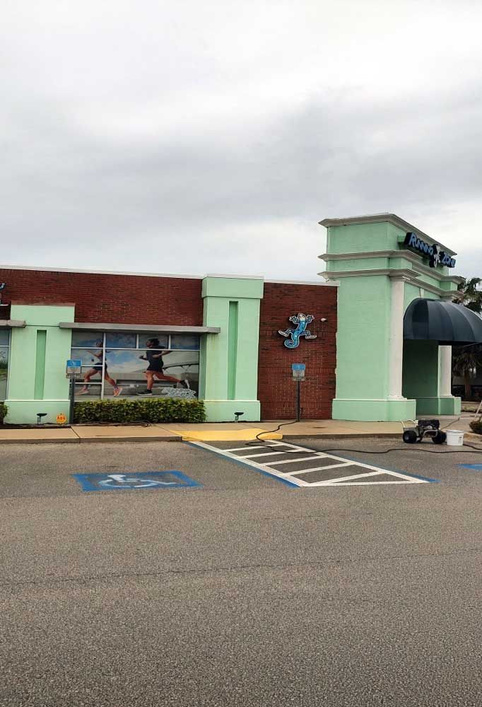 Mint-green storefront with brick accents and a striped accessible parking space in front.