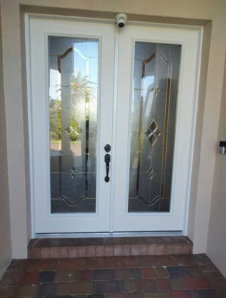 White double front door with decorative glass panes and brick step at the entrance