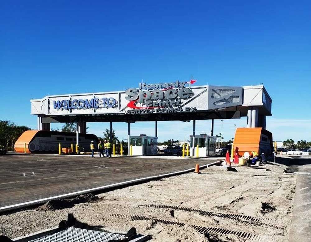 Damaged toll plaza entrance with debris and orange barriers under a bright blue sky