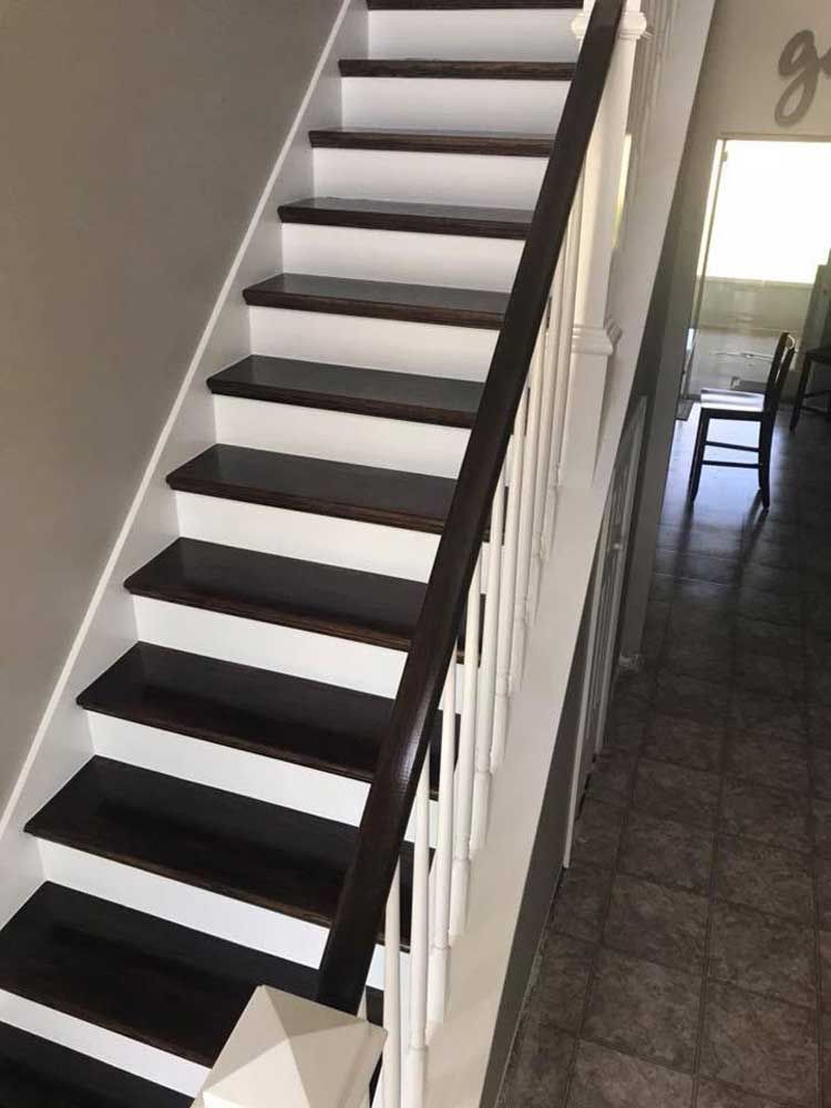 Steep black-and-white staircase in a narrow hallway with a view into a tiled room beyond
