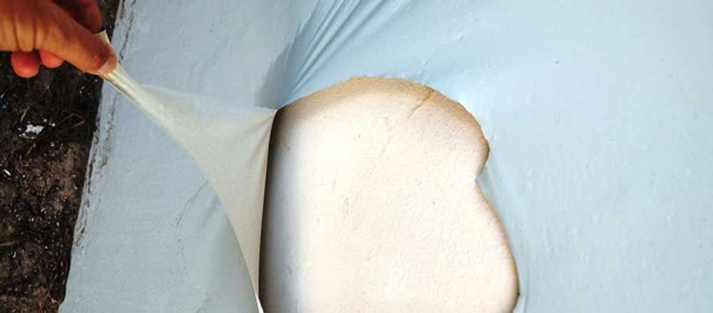 Hand holding clear plastic over a white rounded object against a blue background