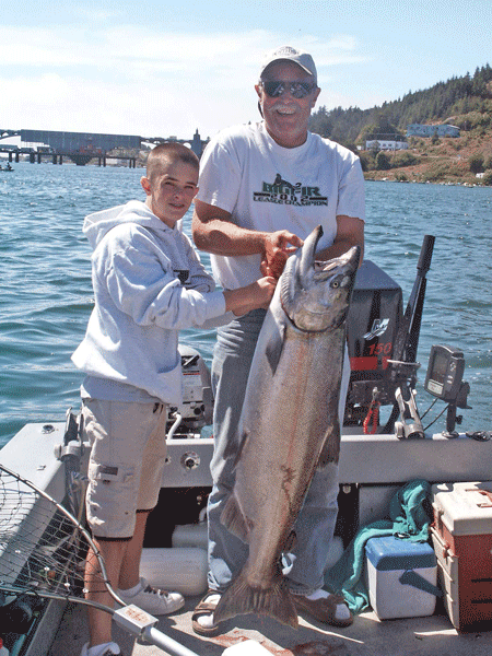 Man and A Boy Are Holding a Large Fish on A Boat