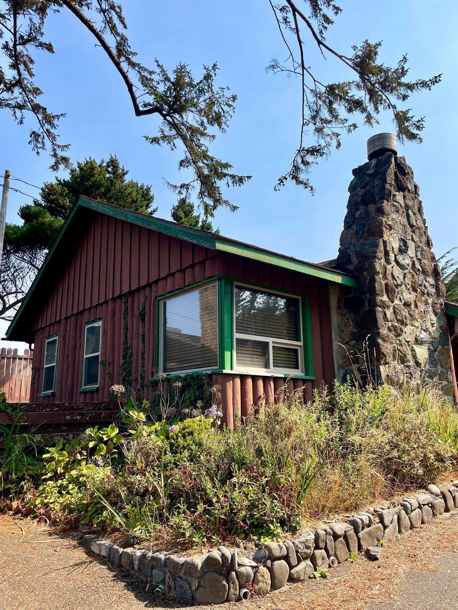 A Brown House with A Green Roof and A Stone Chimney