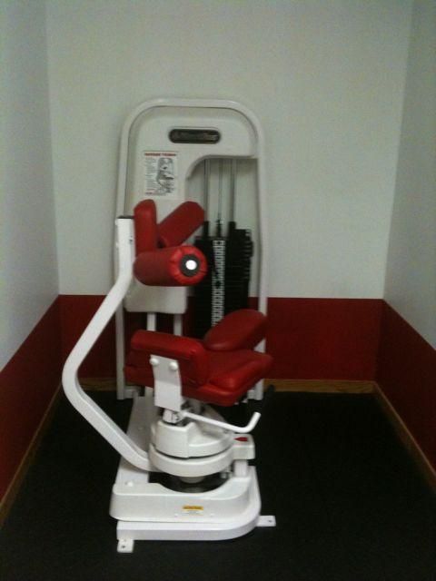 Red and white stairlift chair installed on a stairwell landing, against a white wall with dark red trim.