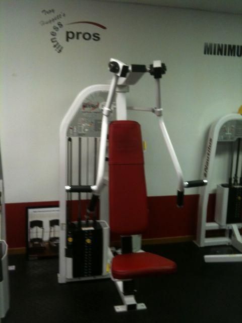 Red and white gym machine with a seat in a fitness room
