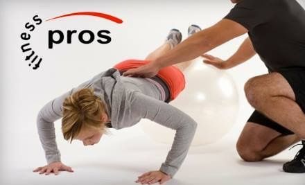 Fitness trainers assisting a person doing a push-up exercise in a bright studio