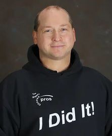 Troy Trainer in a black hoodie with “I Did It!” text, smiling against a plain dark background.