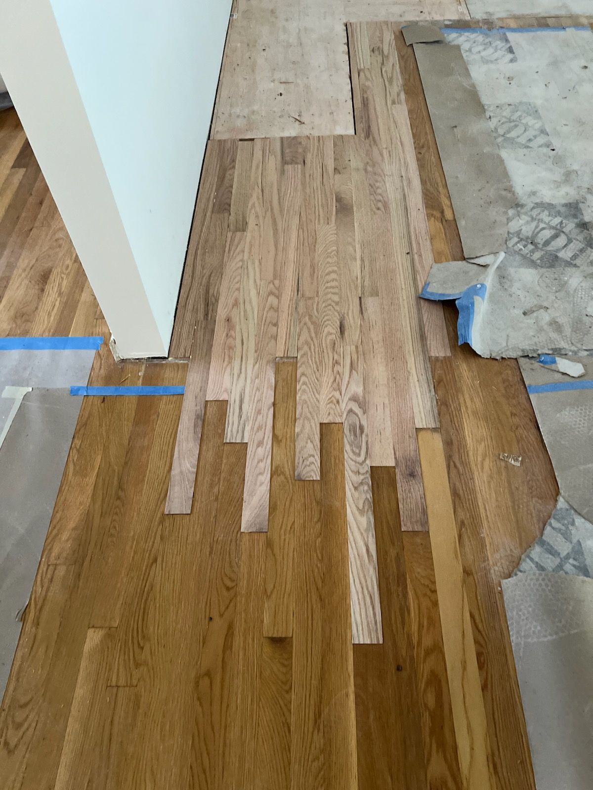 Partially installed wood floor planks meeting unfinished floor beside a room doorway