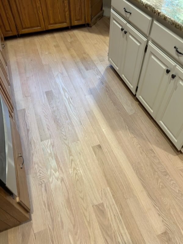 Light oak kitchen floor with white cabinets and wood trim along the edges