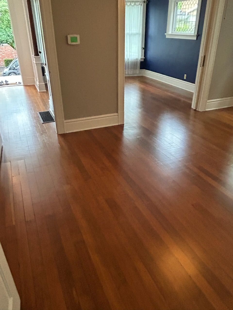 Wood-floored hallway with open doorways and blue-walled room in the background.