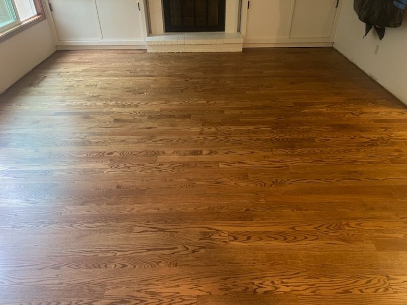 Empty room with polished hardwood floor and a fireplace at the far wall