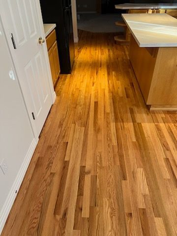 Wooden kitchen floor with white cabinets and a countertop along the right side.