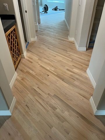 Light wood hallway floor leading to a room with a person in the distance.