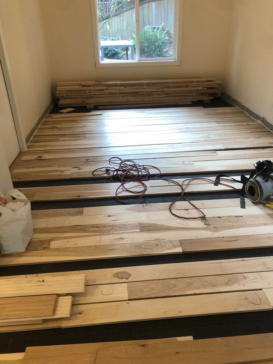Partially renovated room with exposed wooden floorboards and tools scattered on the floor.
