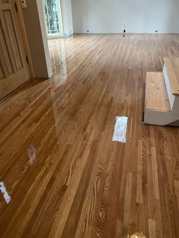 Empty room with glossy hardwood floors and a short staircase on the right.