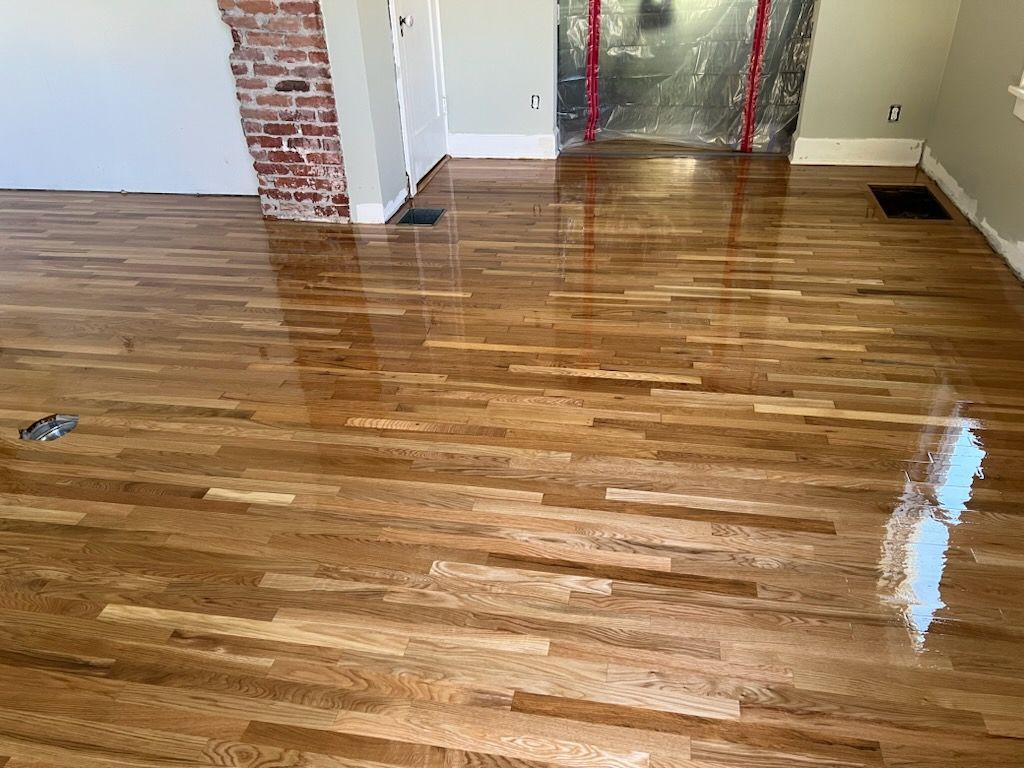 Shiny hardwood floor in an empty room with brick accents and a glass door.
