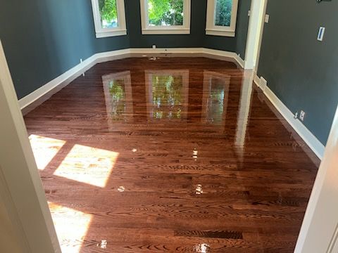 Empty living room with hardwood floors, a beige sofa, coffee table, and large window light