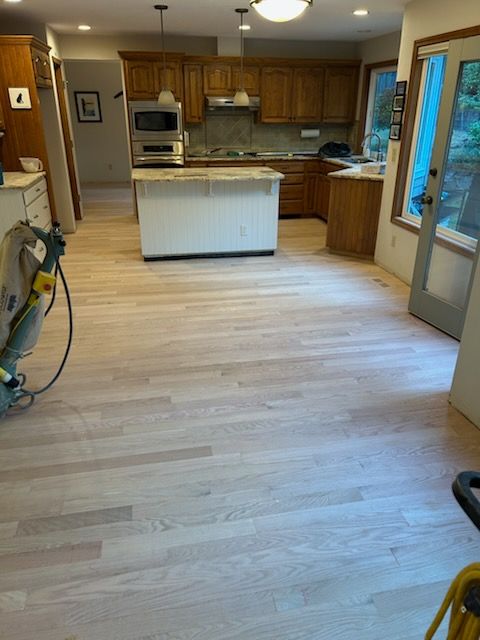 Kitchen with light wood floors, island, wood cabinets, and a doorway to a deck on the right.