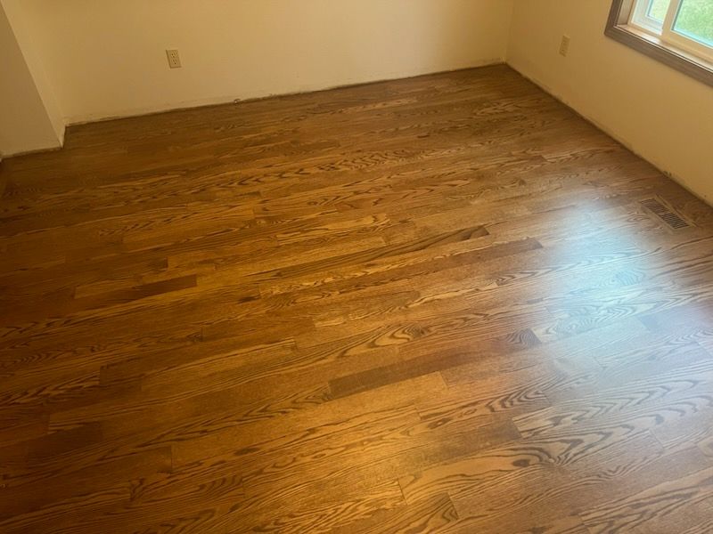 Empty room with hardwood floor and a window letting in sunlight