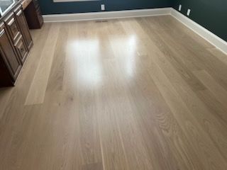 Empty room with light wood flooring, white baseboards, and dark walls, viewed from the corner