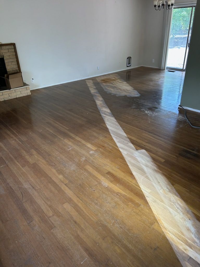Empty living room with hardwood floors and sunlight streaming in through a doorway.