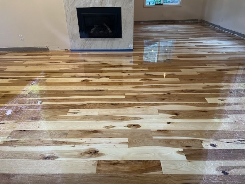 Recently refinished hardwood floor in an empty room with a fireplace.