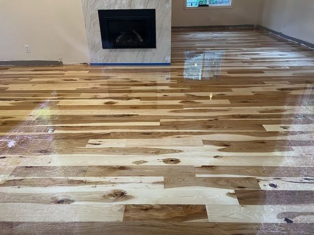 Empty room with dark wood floors and a large window in natural light