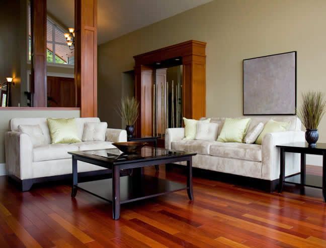 Modern living room with white sofas, dark coffee table, and glossy hardwood floors