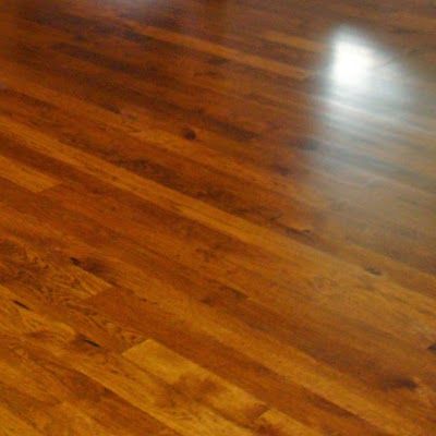 Shiny hardwood floor with warm brown wood grain and a bright light reflection