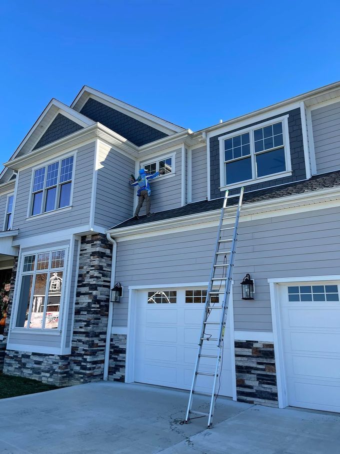 Two-story house with a ladder leaning against the front, under a bright blue sky