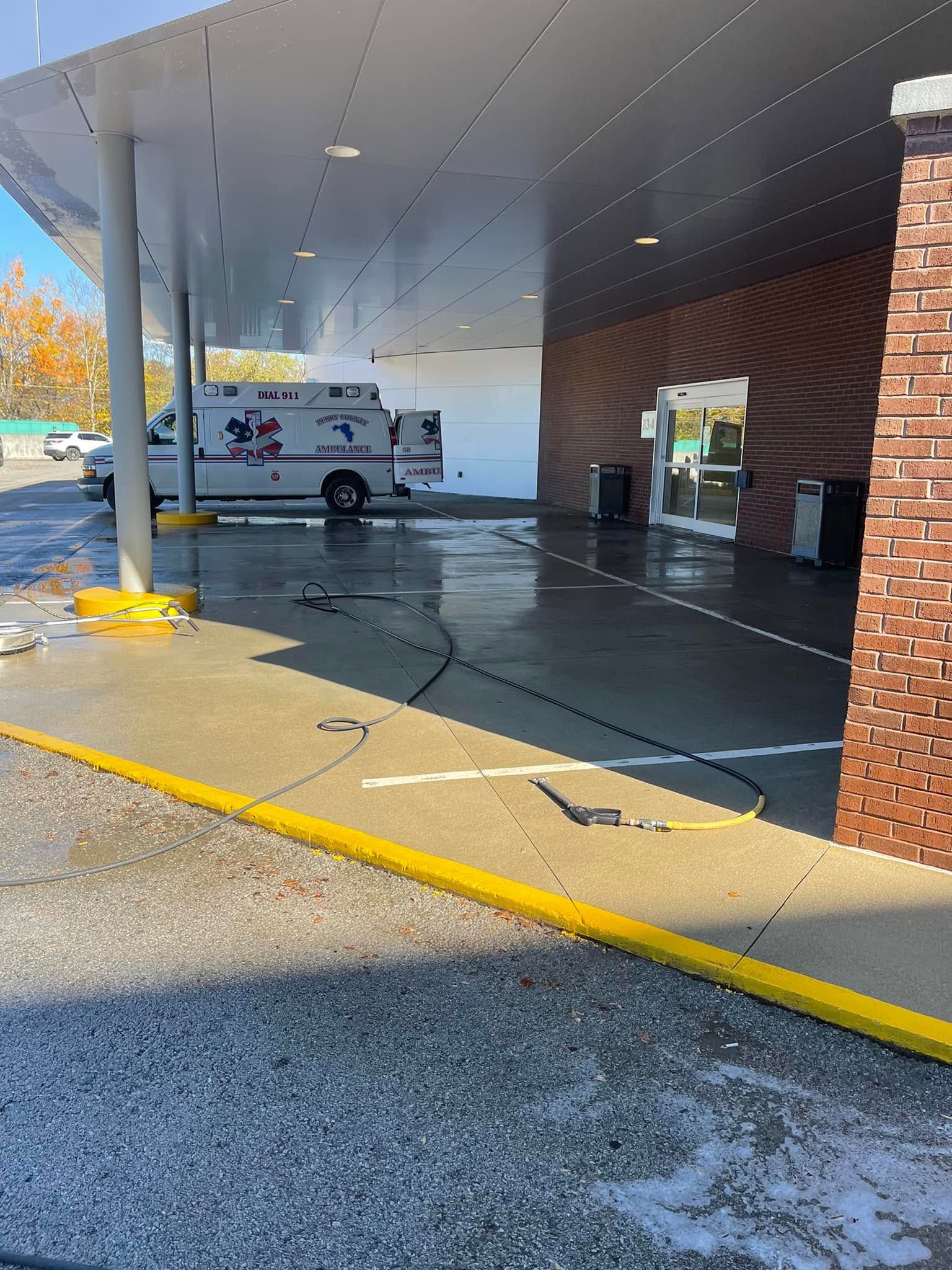 Covered drive-through area with an ambulance parked under a canopy beside a brick building