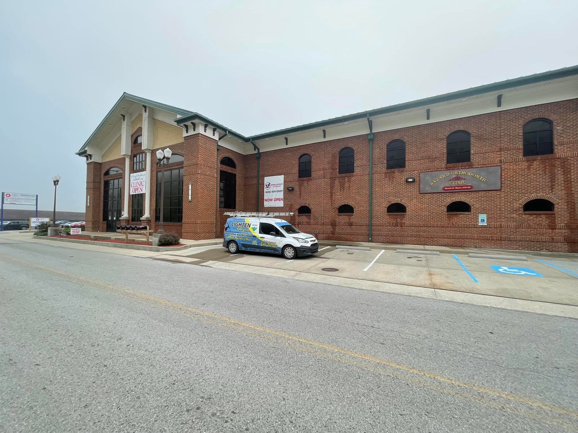 Brick building with a covered entrance and a white-and-blue van parked in front