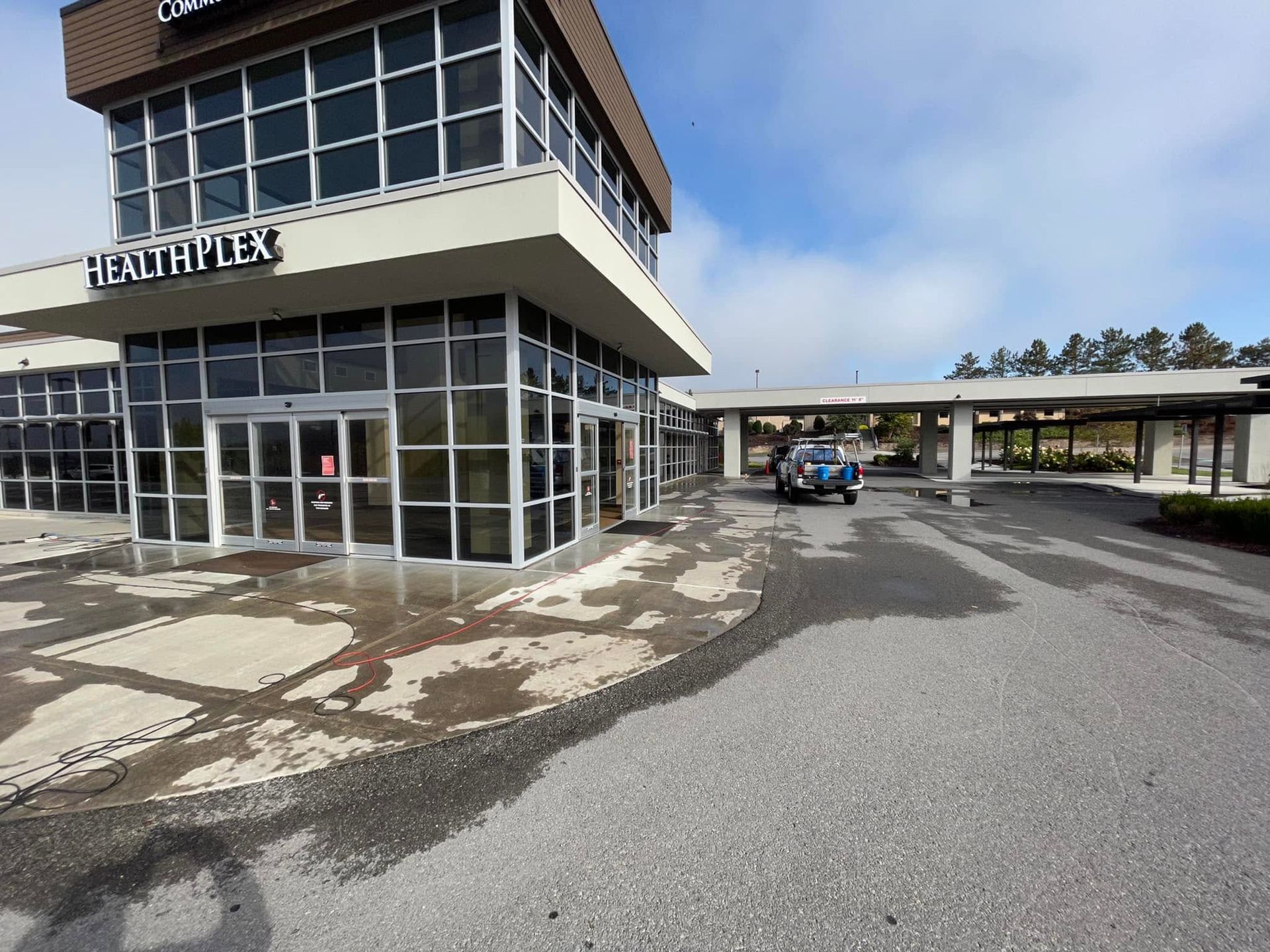 Empty airport terminal entrance with glass windows and a covered drive-through lane under a blue sky