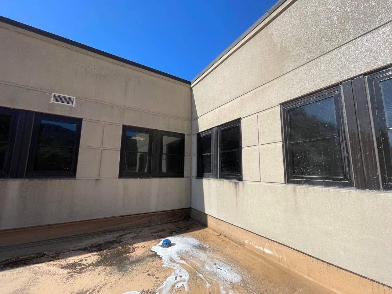 Sunny courtyard between beige buildings with dark windows and a small patch of snow on the ground