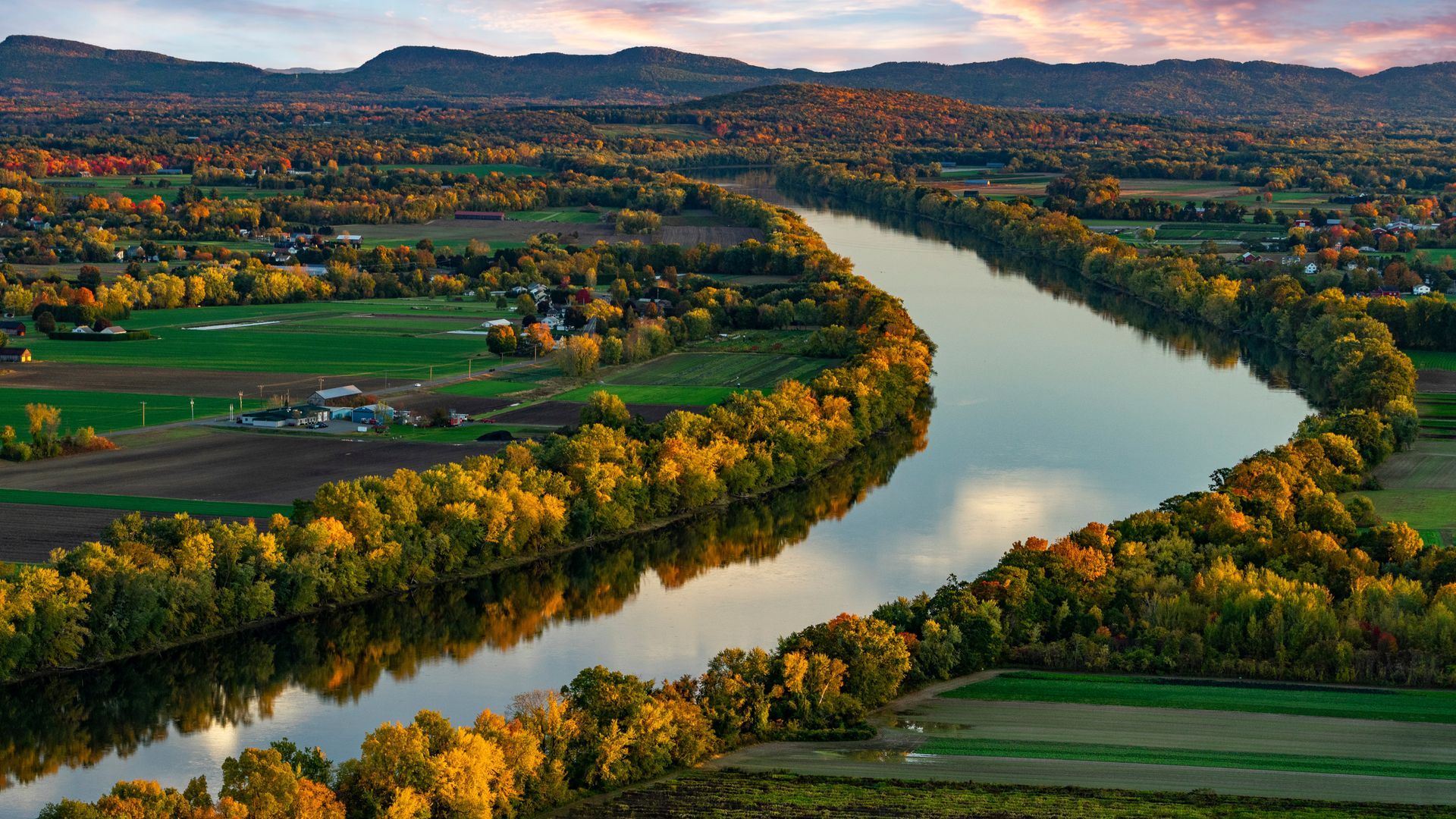 An aerial view of a river surrounded by trees and fields.