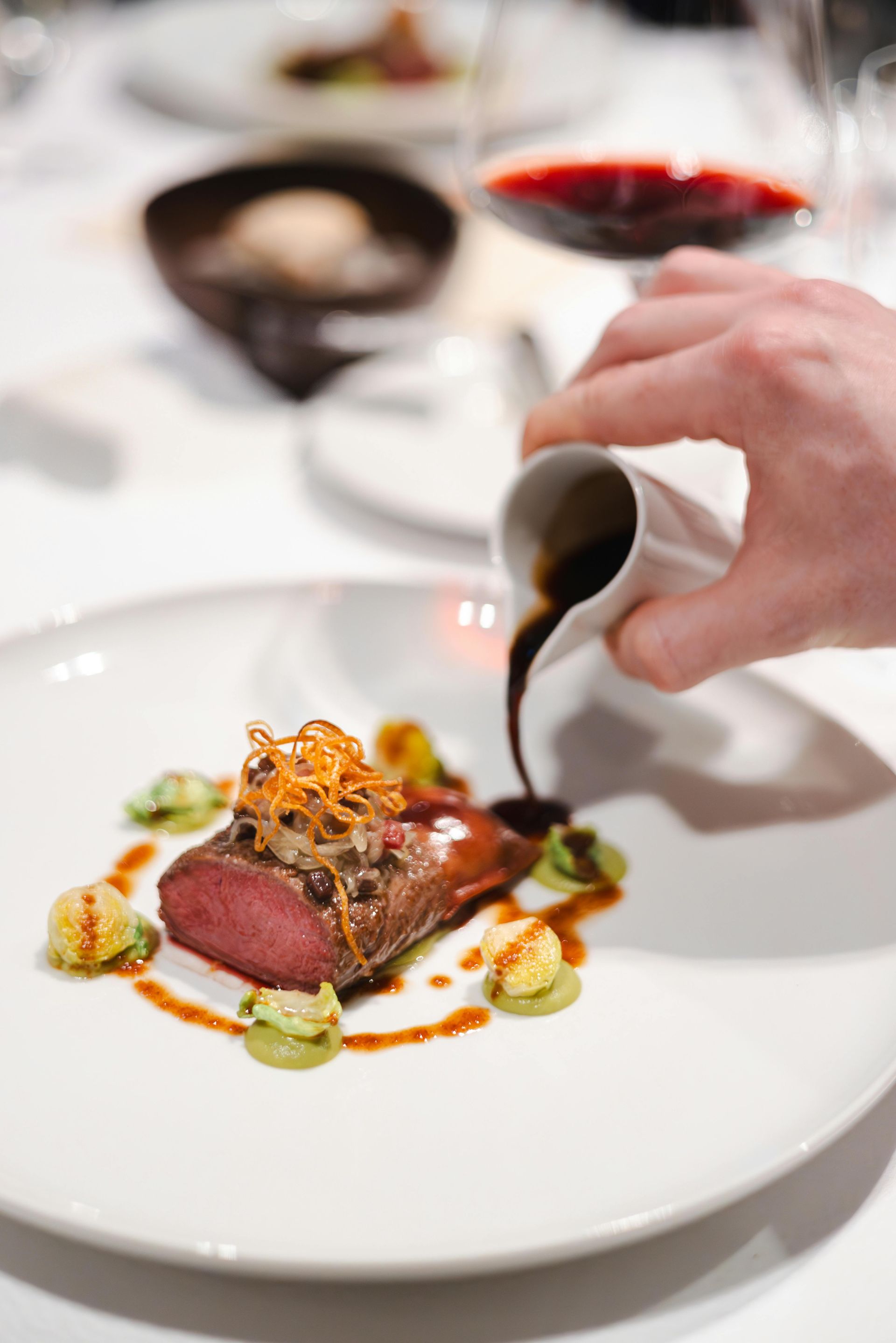 A person is pouring sauce on a plate of food.
