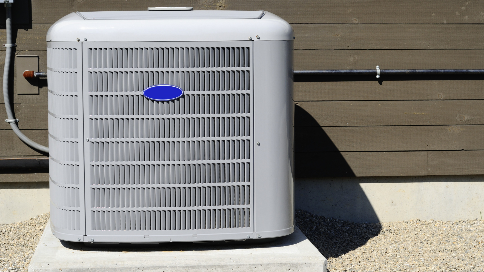 An open HVAC rooftop unit showing two red compressors, electrical components, and wiring, with palm trees in the background.