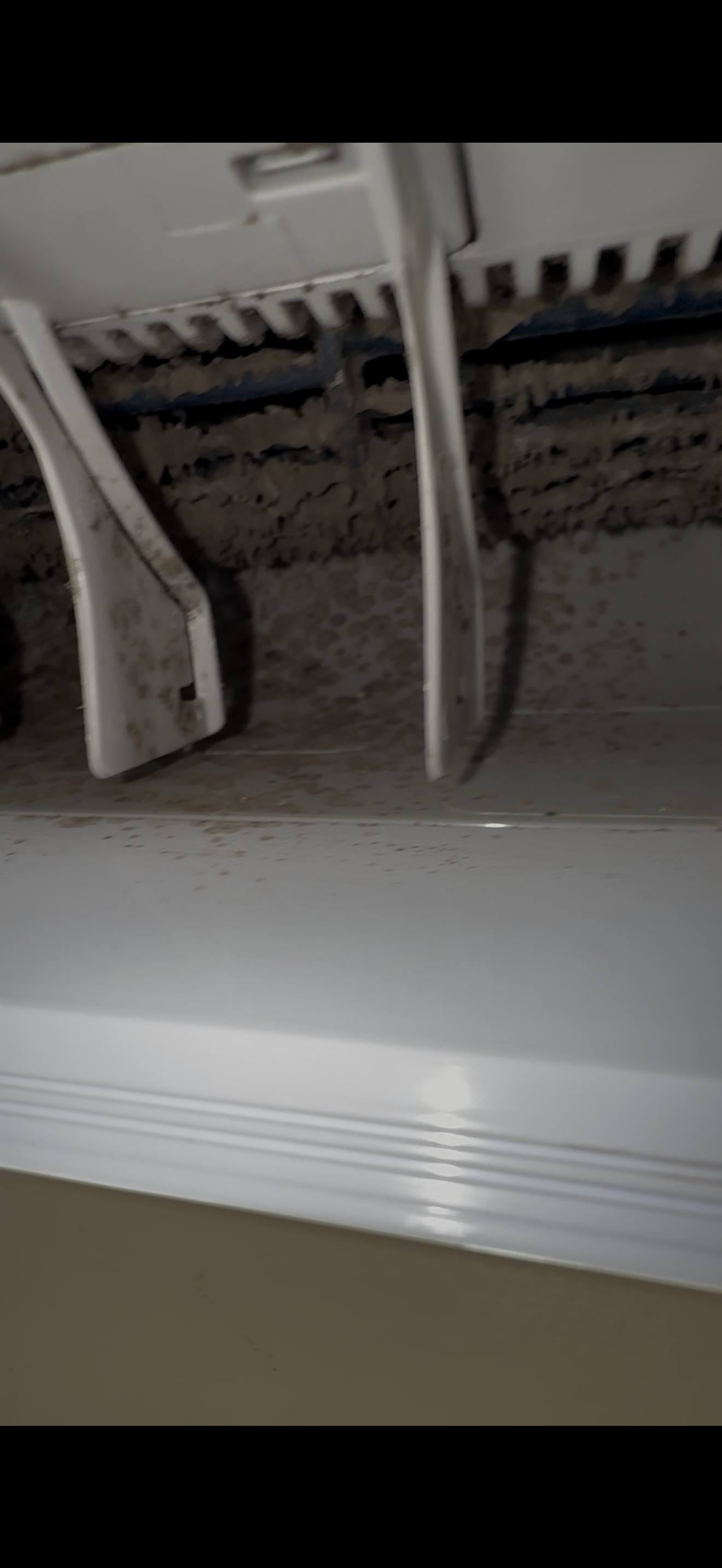 A close-up view of the interior vents of an air conditioning unit, showing a heavy accumulation of grey dust and debris.
