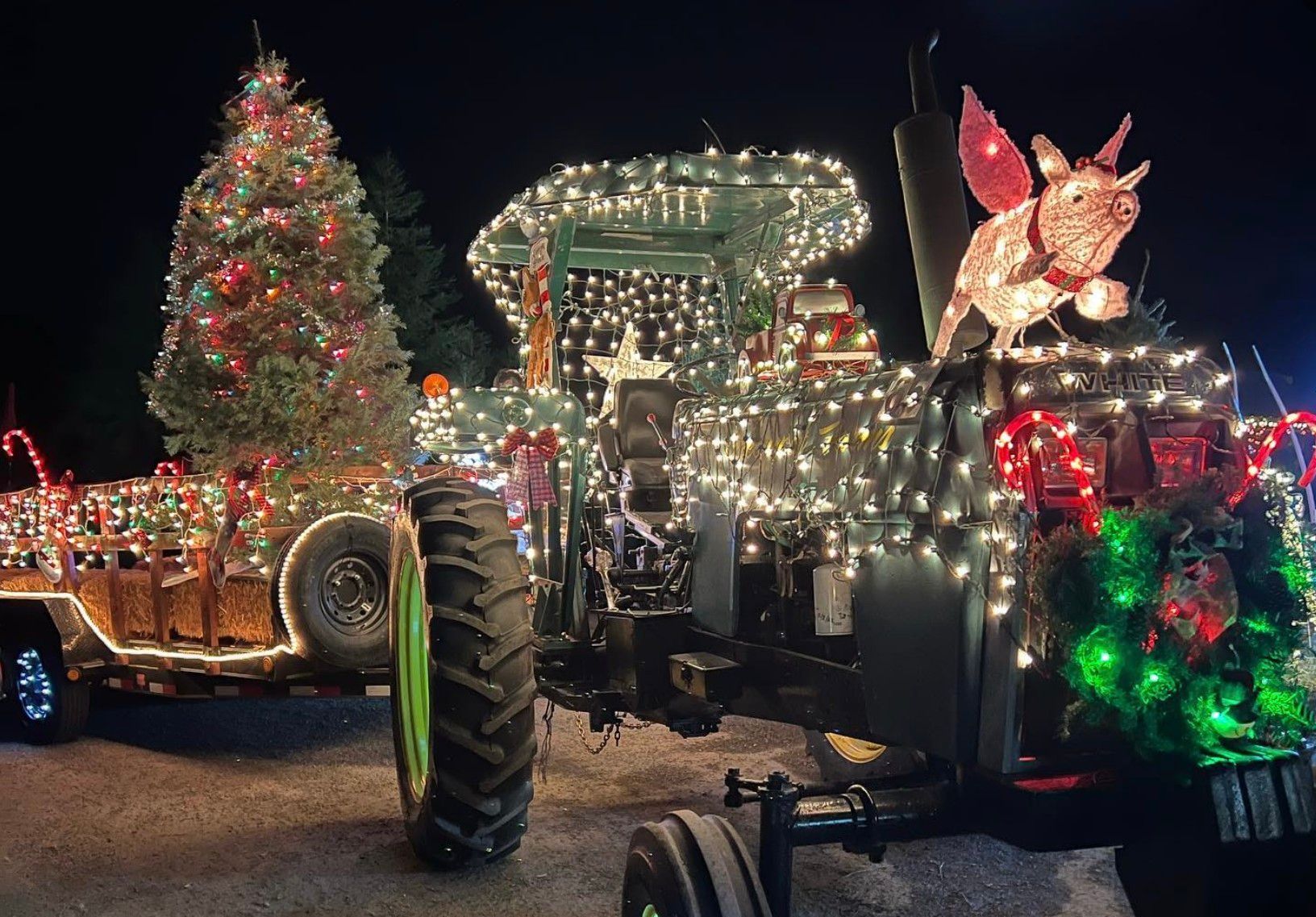 A tractor is decorated with christmas lights and a christmas tree.